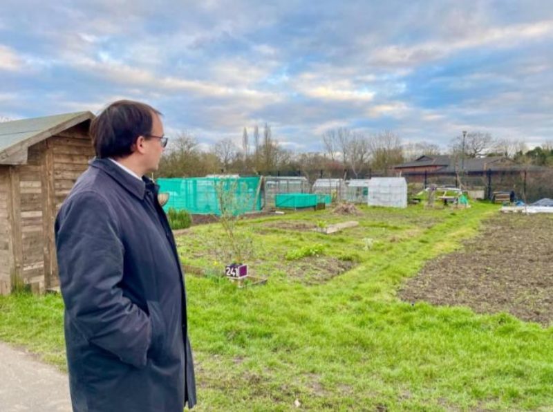 Gareth Thomas MP looking on at the site of 265, The Ridgeway from West Harrow allotments