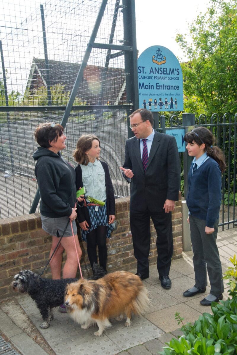 Gareth Thomas with parents and pupils outside St Anselms Catholic Primary School